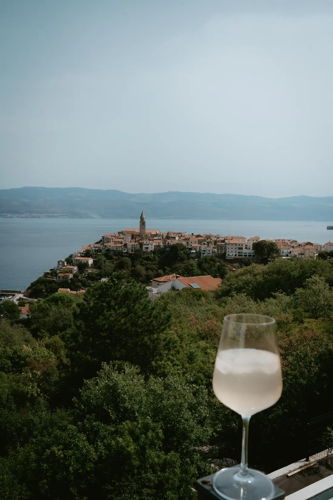 A glass of Žlahtina with a view of Vrbnik
